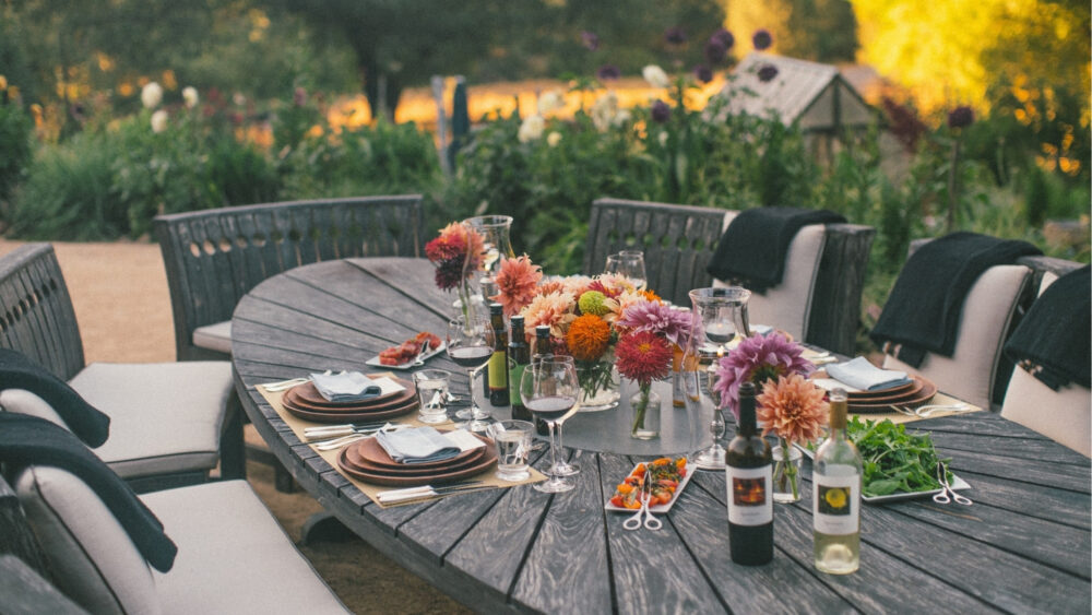 Outdoor dining table prepared for dinner at sunset in the garden at NewTree Ranch in Sonoma County.