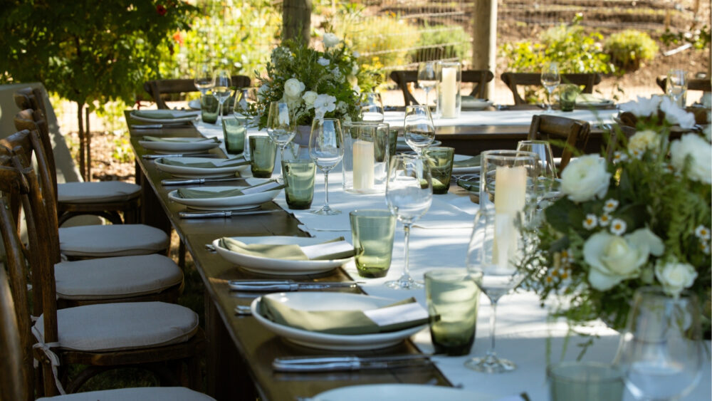 Outdoor dining table prepared for an evening meal beneath the trees at NewTree Ranch in Sonoma County.